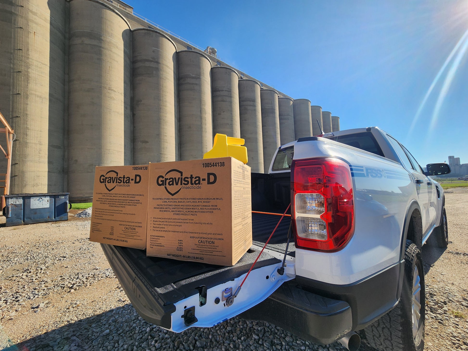 White FSS, Inc. truck with Gravista-D boxes in the back, silos in the background