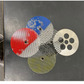 Four circular metal filters with different patterns on a metallic surface