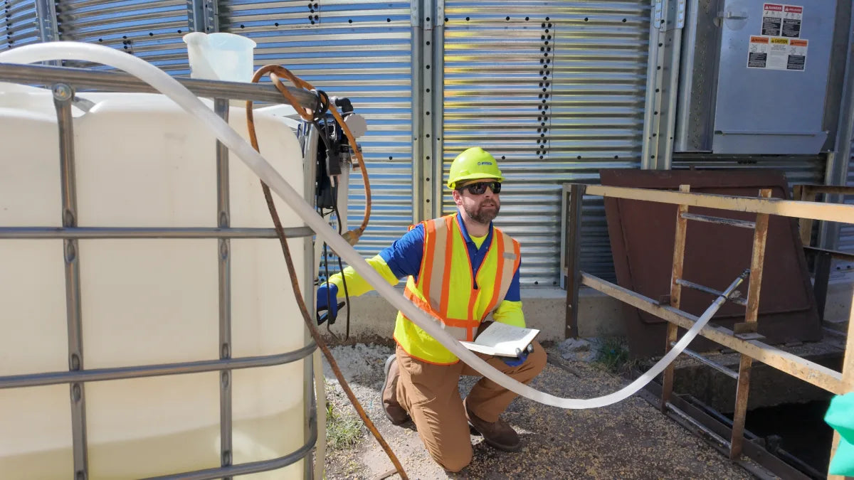 FSS technician checking a tank-mix application setup at a grain bin receiving pit
